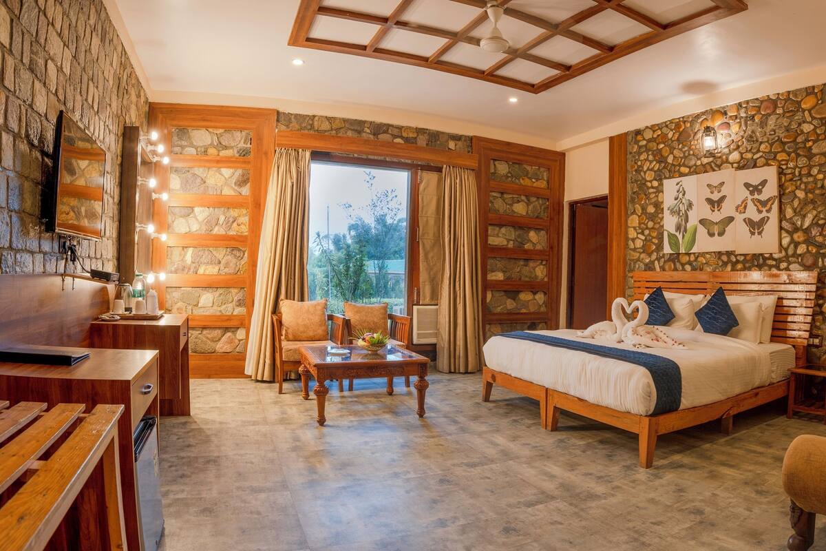 A spacious bedroom with a large bed, wooden headboard, and a stone wall with butterfly artwork.