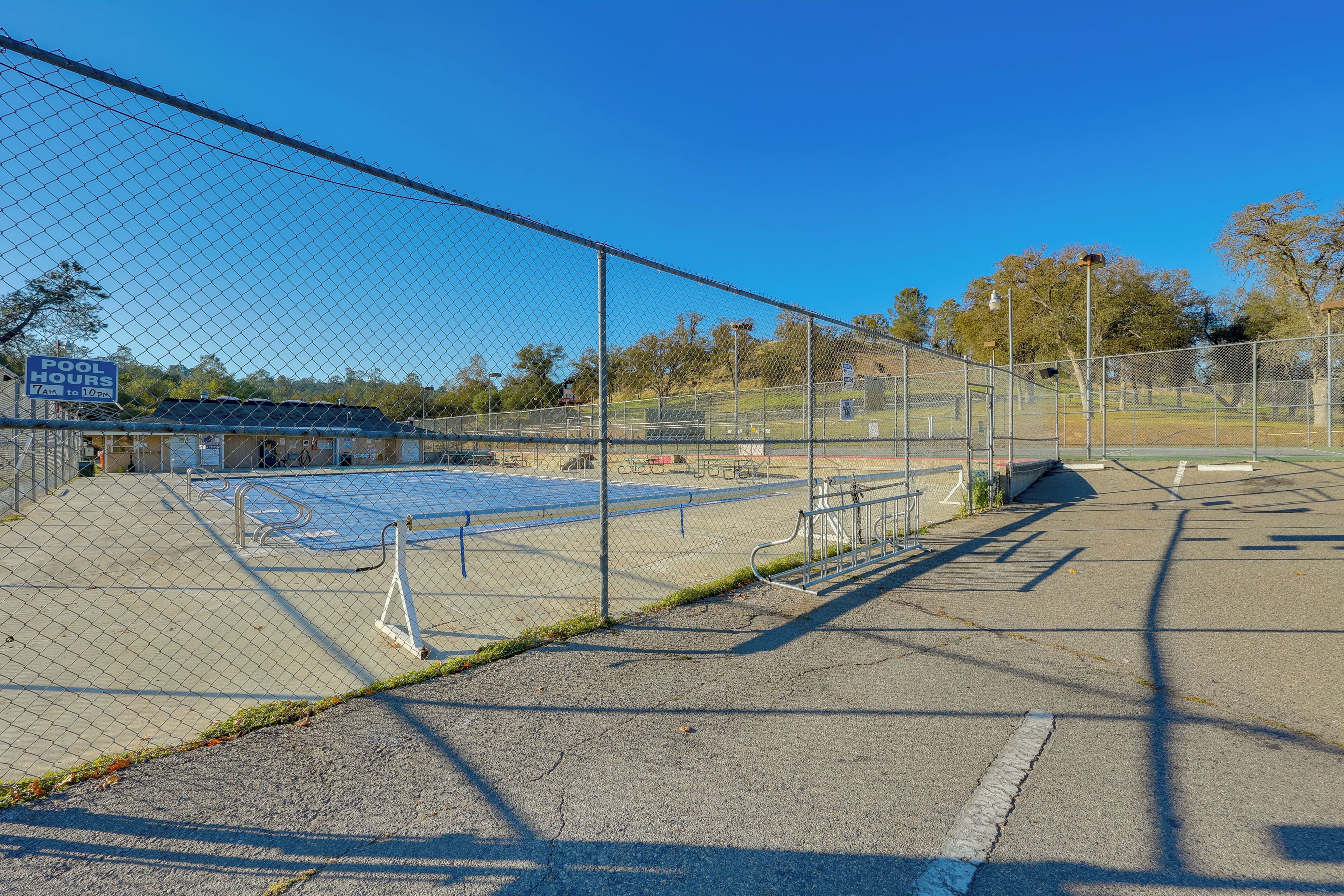 A fenced sports court with a sign indicating "HOOD HOURS" and a building in the background.
