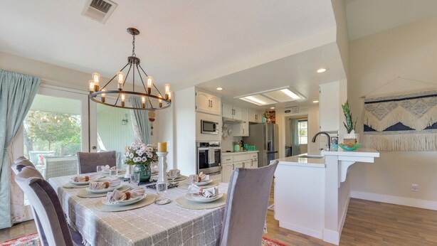 Un comedor con una mesa preparada para cuatro personas, un candelabro y una cocina al fondo.