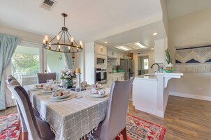 Un comedor con una mesa preparada para cuatro personas, un candelabro y una cocina al fondo.