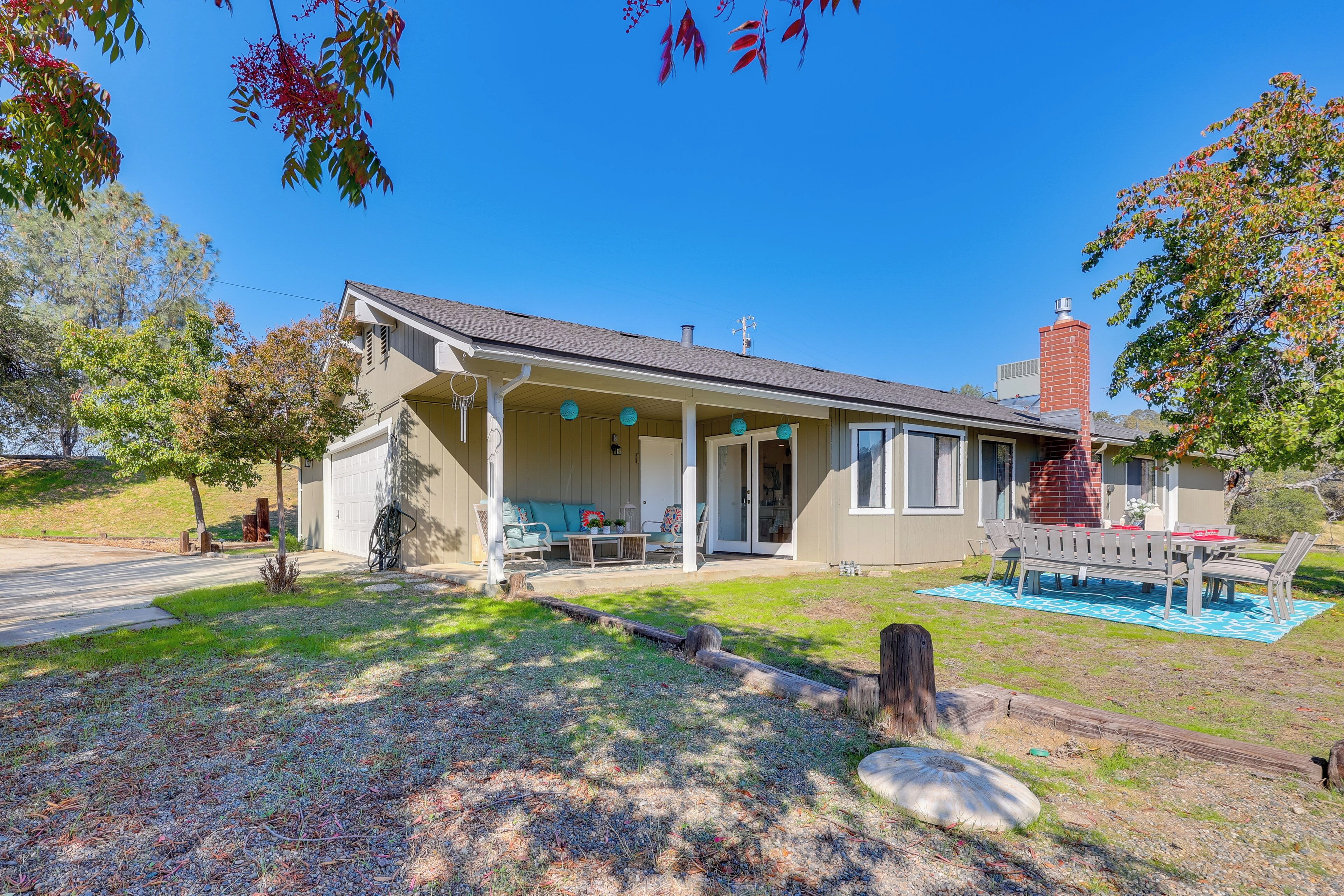 A two-story house with a covered porch, a brick chimney, and a small front yard with a picnic table and chairs.