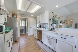 Una cocina moderna con armarios blancos, electrodomésticos de acero inoxidable y una isla central.