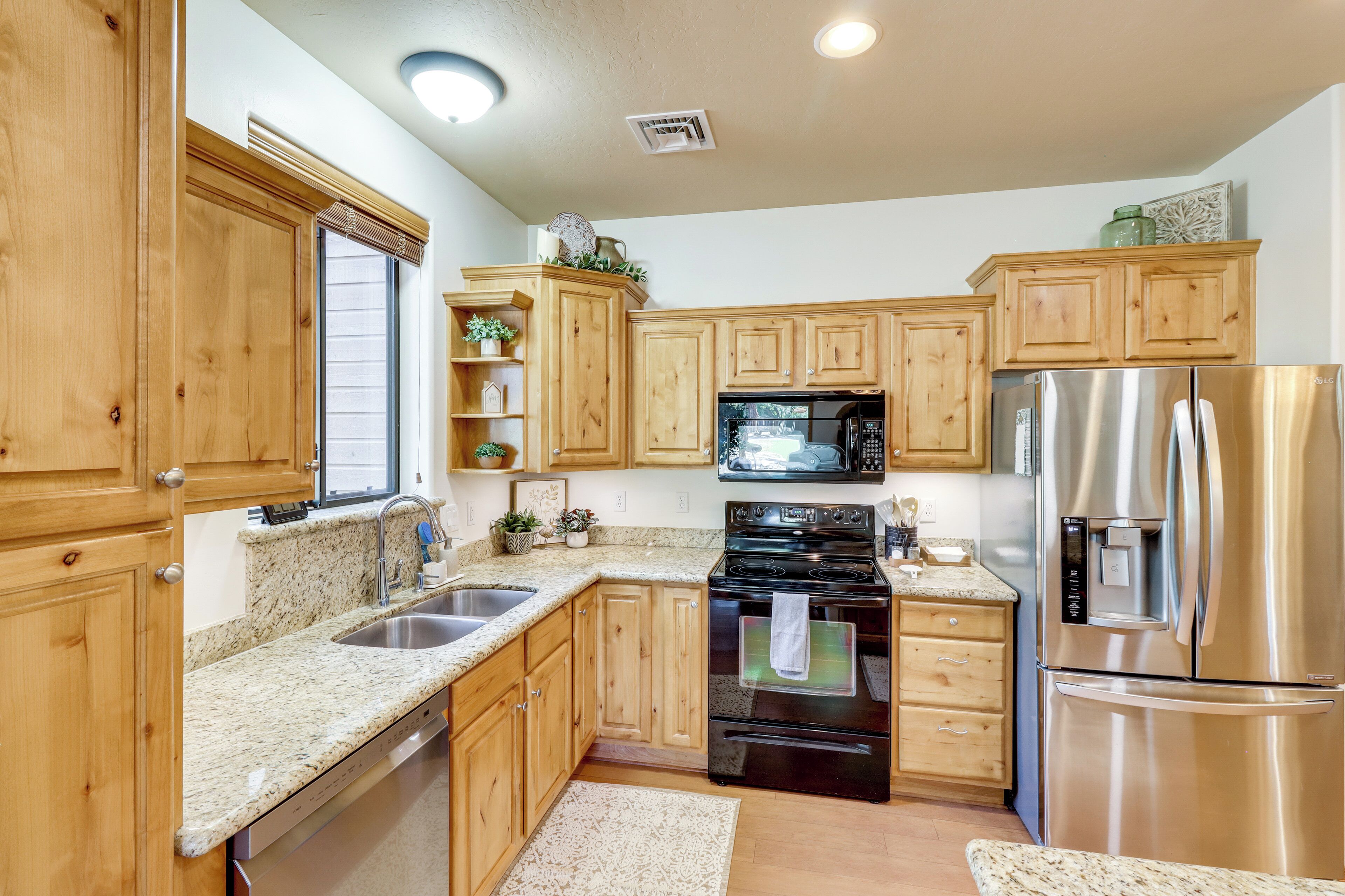 A kitchen with wooden cabinets, a stainless steel refrigerator, a microwave, and a dishwasher.