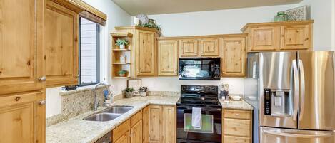 A kitchen with wooden cabinets, a stainless steel refrigerator, a microwave, and a dishwasher.