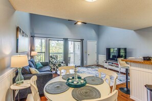 A living room with a dining table, chairs, a TV, and a sofa. - Golf, Gamble & Deep-sea Fish: Little River Condo (Little River)