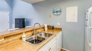 A kitchen with a granite countertop, stainless steel sink, and white cabinets. - Golf, Gamble & Deep-sea Fish: Little River Condo (Little River)