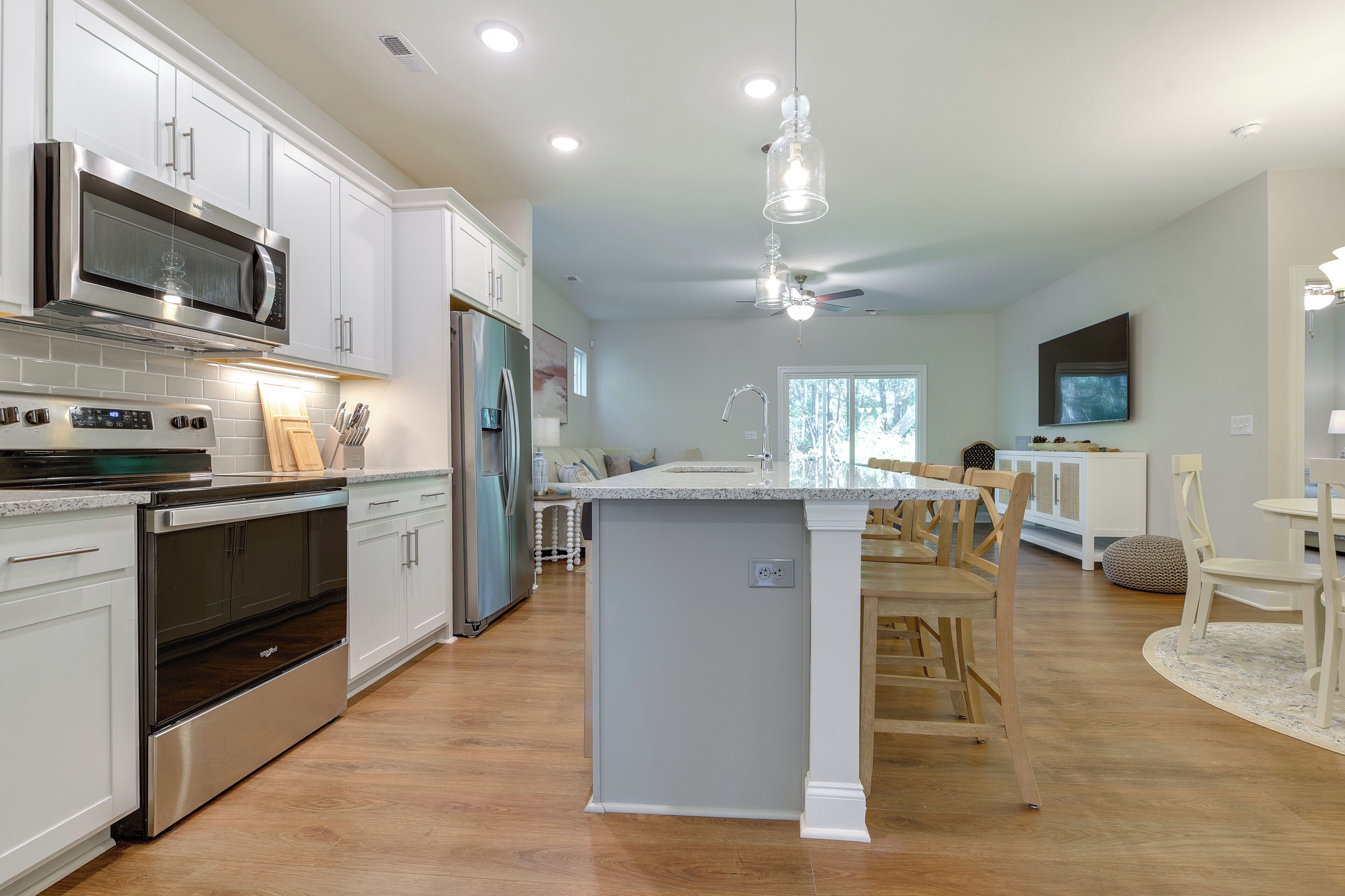 A modern kitchen with stainless steel appliances, a central island, and a dining area with wooden chairs.