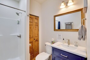 A bathroom with a shower, toilet, sink, and mirror.