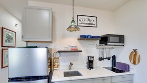 Eine moderne Küche mit einem Edelstahl-Kühlschrank, einer Mikrowelle, einem Spülbecken und einer Kaffeemaschine.