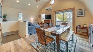 A spacious living area with a dining table, comfortable seating, a fireplace, and a large window providing natural light. - Private Dock & Fire Pit: Beautiful Lake Setting (Bradford)