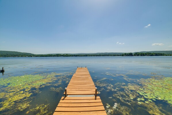 A wooden pier extending into a lake with calm water and distant green hills. - Private Dock & Fire Pit: Beautiful Lake Setting (Bradford)