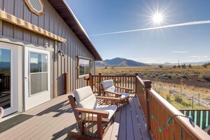 Une terrasse en bois avec deux chaises et une table, offrant une vue sur un paysage montagneux.