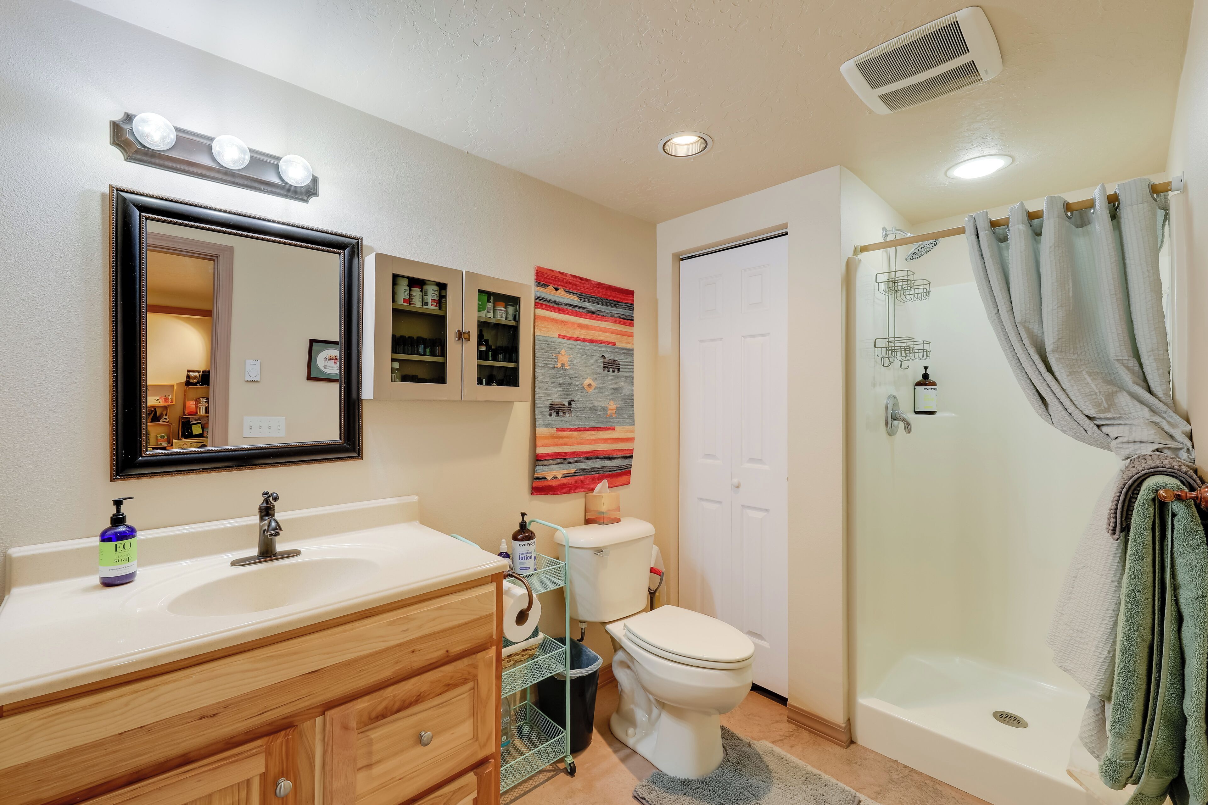 Une salle de bain comprenant un meuble-lavabo, un évier, un miroir, des toilettes, une douche et un porte-serviettes.
