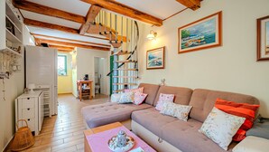 A cozy living room with a sofa, a table with a decorative item, a staircase, and a painting on the wall. - Villa Ruby beachfront by Villas Guide (Dobrinj)