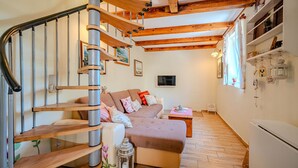 A spiral staircase with wooden steps and metal railings, a beige sofa with cushions, a small table with a lamp, and a white refrigerator. - Villa Ruby beachfront by Villas Guide (Dobrinj)