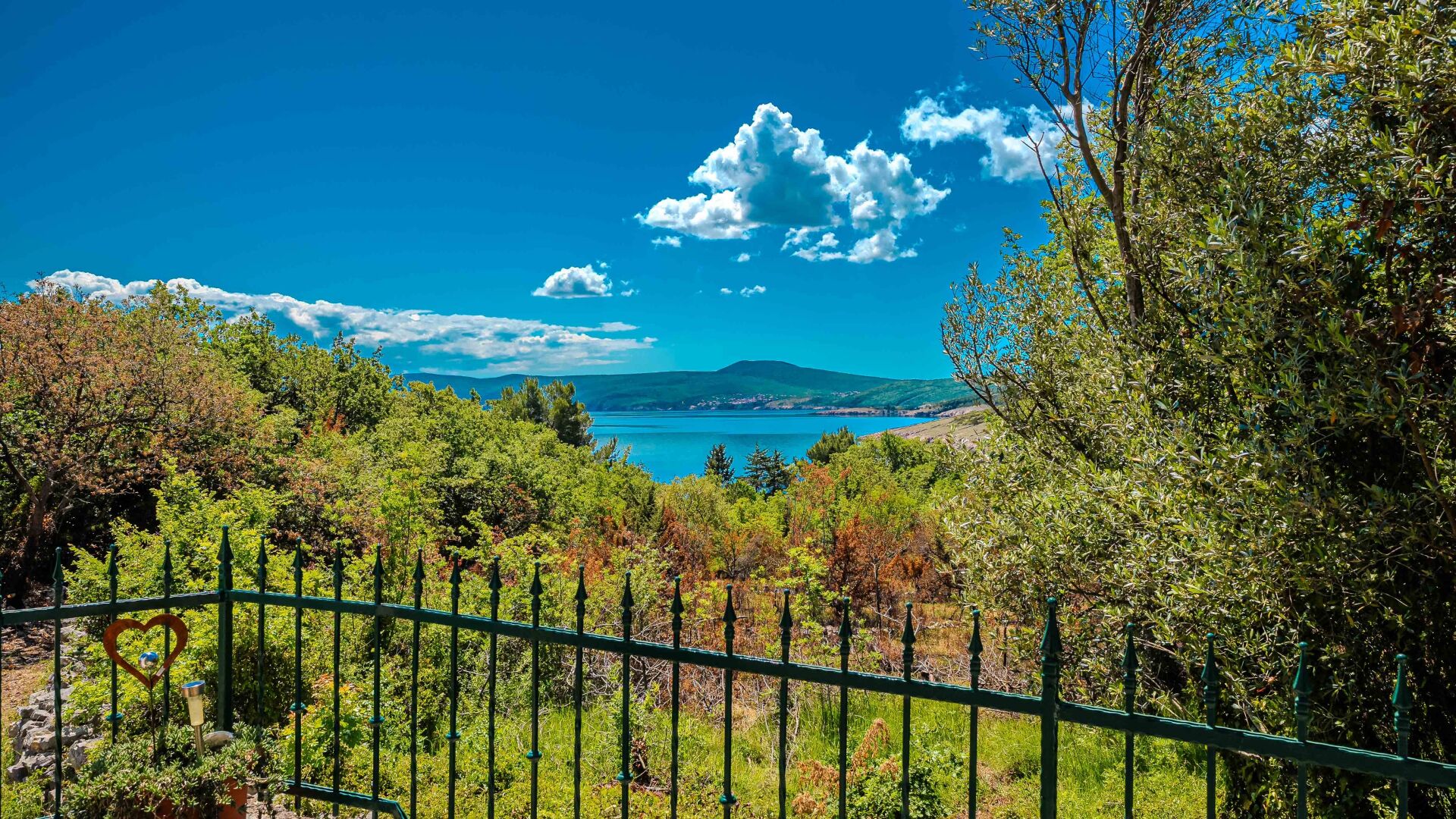 A scenic landscape with a clear view of a body of water, a distant mountain, and lush greenery.