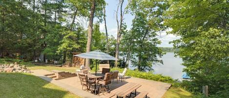 A deck with outdoor furniture, a table, and chairs, overlooking a lake.