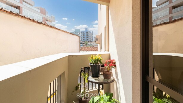 Un balcón con plantas en macetas y vista a edificios al fondo.