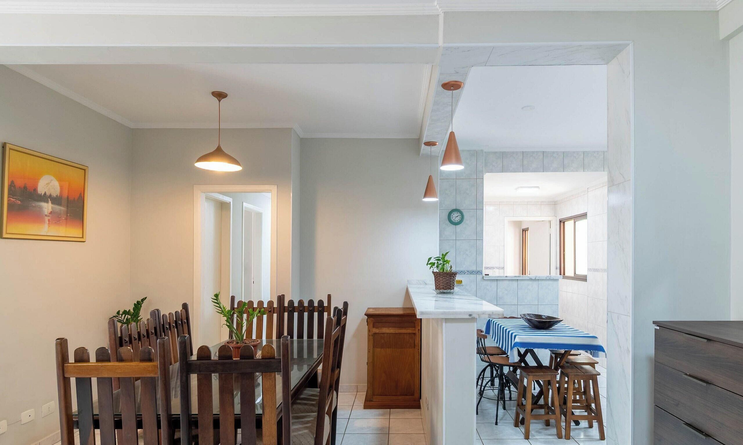 A modern kitchen with a central island, wooden chairs, and pendant lighting.
