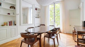 A dining area with a wooden herringbone floor, white cabinetry, and a large window with curtains. - IMMERSE YOURSELF IN THE AUTHENTIC PARISIAN LIFESTYLE AT BLVD SAINT GERMAIN (Paris)