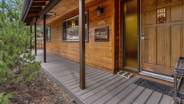 A wooden cabin with a wooden deck, a welcome sign, and a door with a number.