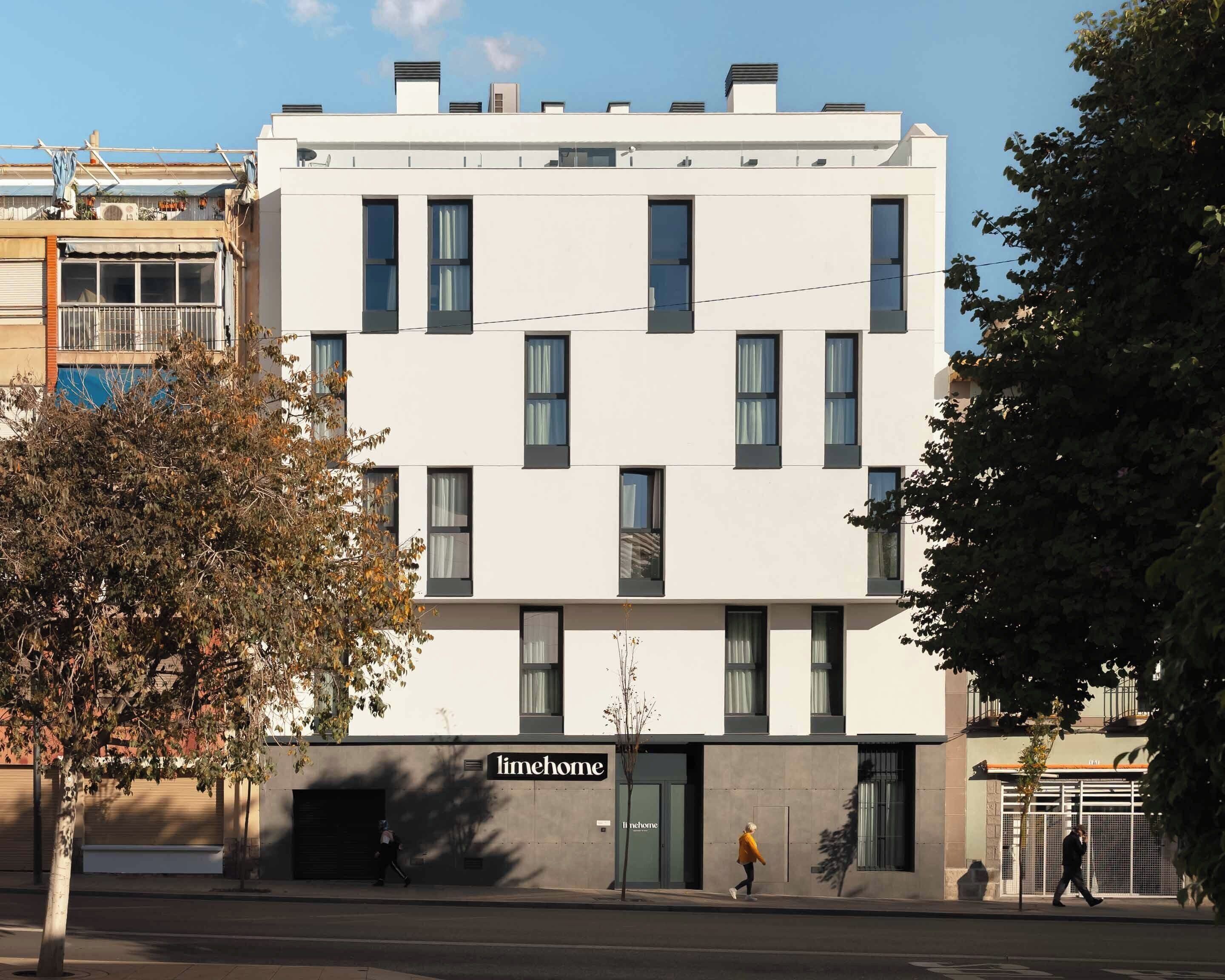 A modern building with a flat facade, multiple windows, and a sign reading "limehome".