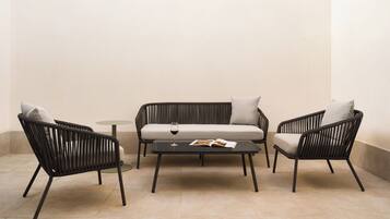 Un espace extérieur moderne, aménagé avec un canapé, deux fauteuils et une petite table ronde.