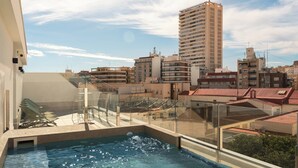A rooftop pool with a glass balustrade, surrounded by urban buildings and a clear sky. - Limehome Alicante Avinguda de Jijona (Alicante)