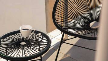 Two black metal chairs with round glass tables on a tiled patio.
