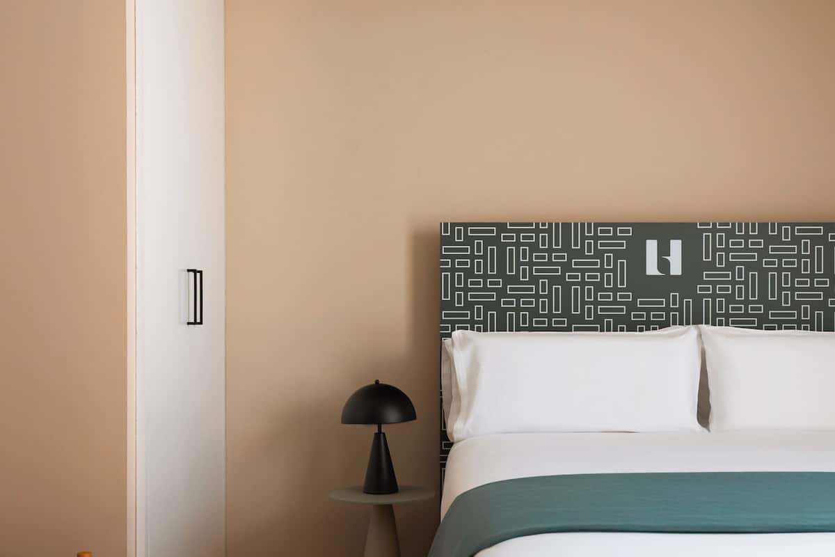 A bedroom with a bed, a bedside table with a lamp, and a wooden bench.