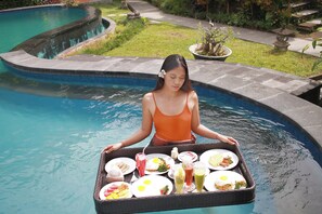 Una donna serve la colazione a bordo piscina con un vassoio di cibo e bevande.