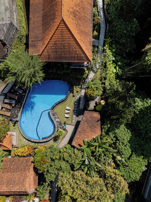 An aerial view of a residential area with a swimming pool, tiled roofs, and lush greenery. - ABANGAN BUNGALOW  (Ubud)