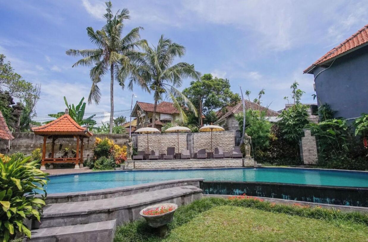 A swimming pool with a gazebo, palm trees, and a stone wall.