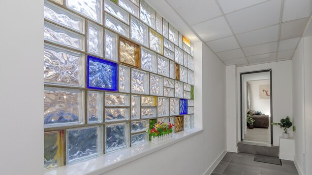 A hallway with a large window featuring colorful glass panels and a small plant on the windowsill. - Seaside View Retreat in Clacton-on-sea (Clacton-on-Sea)