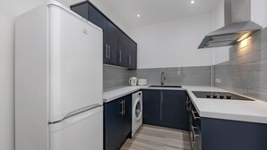 A modern kitchen with a built-in washing machine, a stainless steel range hood, and a white refrigerator. - Seaside View Retreat in Clacton-on-sea (Clacton-on-Sea)