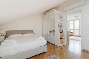 A bedroom with a bed, bedside tables, a wardrobe, and a view of the outside.