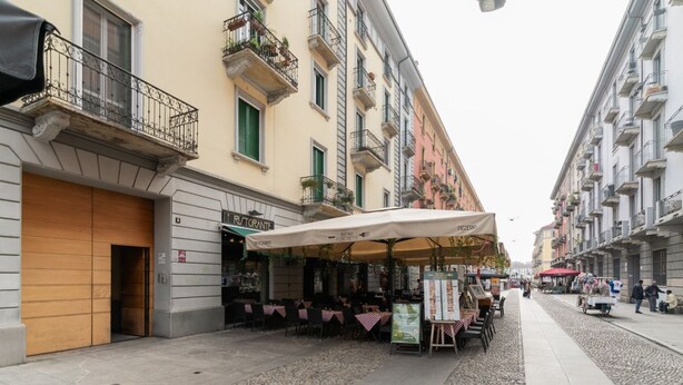 A street with outdoor seating, a restaurant named 'Ristorante,' and a cobblestone street. - GuestHost - Elegant and modern 90 square meters apartment, perfect for four people, located on the fifth floor of a building with elevator (NOT suitable for disabled people).The property is located in the Navigli area (limited traffic zone), one of the c (Milan)
