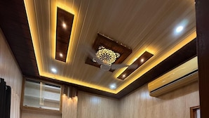 A hotel room with a bed, a red throw blanket, a patterned rug, and a ceiling with recessed lighting and a decorative panel. - SHRI SHYAM KASHI STAY VARANASI (Varanasi)