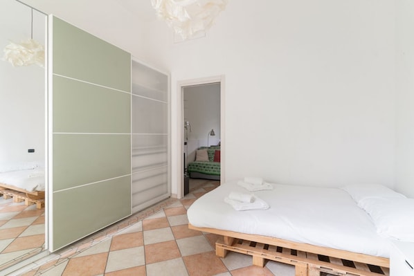 A bedroom with a wooden bed, a green sliding door, and a tiled floor.
