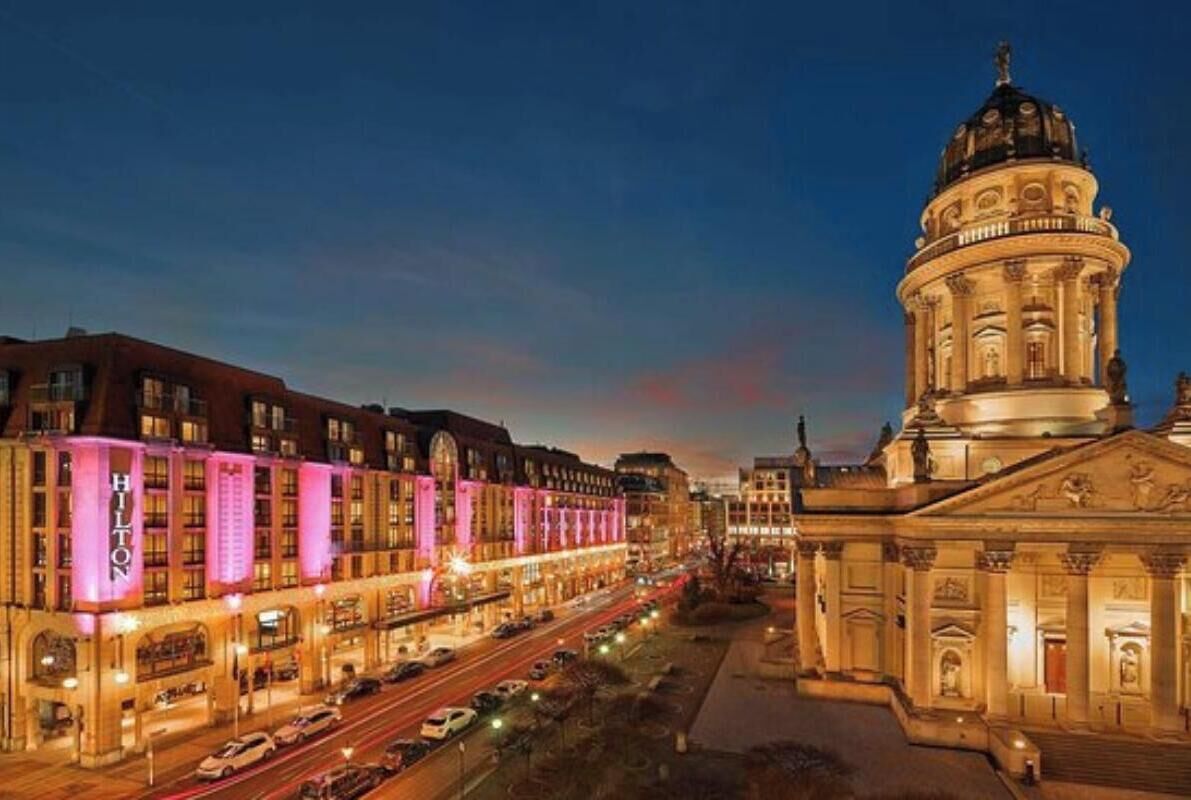 A hotel with a classical facade, a large dome, and a street view with cars.
