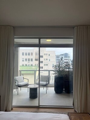 Ein Hotelzimmer mit Balkon, zwei Stühlen, einem kleinen Tisch und einem Blumentopf.