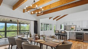 A modern kitchen with white cabinets, a stainless steel refrigerator, and a dining area with a wooden table and chairs. - Alexander Valley | Hot Tub, Pool & Pickleball (Cloverdale)