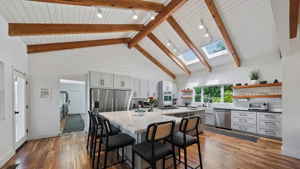 A spacious kitchen with a central island, wooden beams, and a skylight. - Alexander Valley | Hot Tub, Pool & Pickleball (Cloverdale)