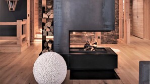 Ein modernes Interieur mit Kamin, Holzbalken und einem Steinelement.