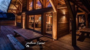 Eine Holzhütte mit einer überdachten Terrasse, großen Fenstern und einem Essbereich.