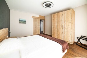 A bedroom with a bed, wooden wardrobe, and a view of a mountain landscape.