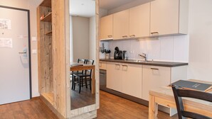 A modern kitchen with white cabinets, a wooden dining table, and a built-in oven. - Wohntel - wohnen wie im Hotel (Sevelen)