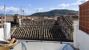 A rooftop with terracotta tiles, a white wall with a decorative pattern, and a mountainous landscape in the background. - Casa Julieta (Viver)