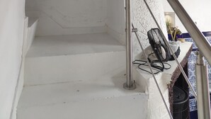A white staircase with a metal handrail, a pink abstract painting on the wall, and a blue and white tiled area at the bottom. - Casa Julieta (Viver)