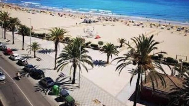 A beach with palm trees, a parking lot, and a view of the ocean. - Casa Julieta (Viver)